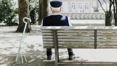 Anerkennung Nachwuchs – Dreibein Alter Mann auf einer Bank mit Gehstock.