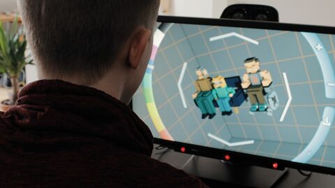 Mann von hinten sitzt vor einem Bildschirm mit Comic-Figuren.