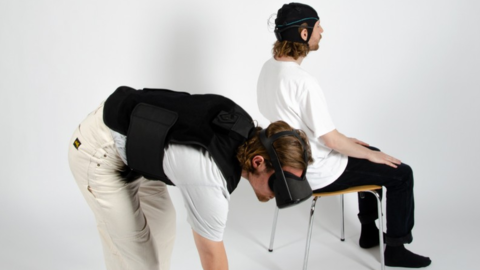 Zwei junge Männer mit VR-Brillen. Einer auf einem Stuhl sitzend, einer sich bückend. 